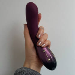 Hot Octopuss Kurve dual motor vibrator held in a white person's hand.