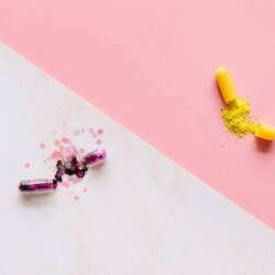 Decorative image of two pills with sparkles exploding out against a white and pink background.