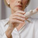 An older woman holding white vibrator, the camera focused on her hands.